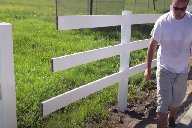 Fence worker installing vinyl rail fence